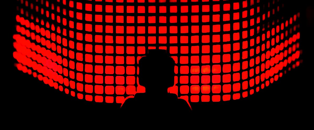 Silhouette of a person against a glowing red digital grid